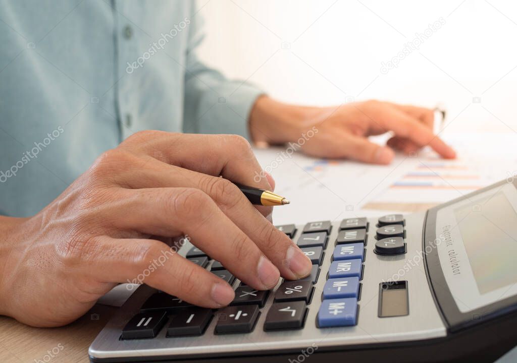 A business man using a calculator to calculate expenses from receipts placed on the table. debt concept