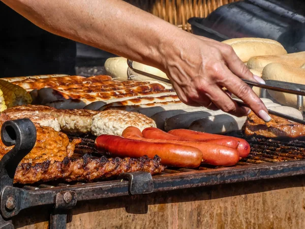 Churrasco: Mulher prepara salsichas e bifes — Fotografia de Stock