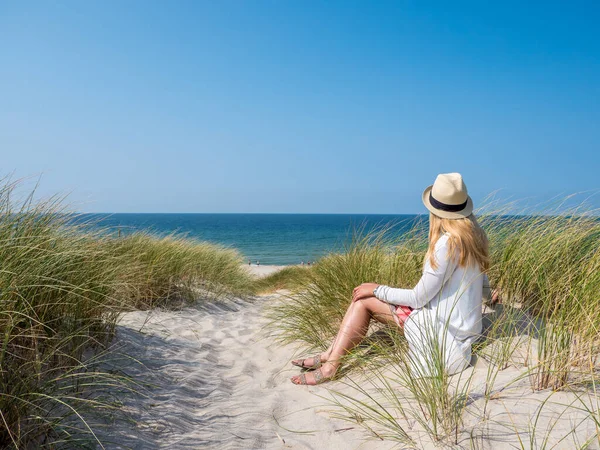 Frau sitzt im Sand und beobachtet das Meer — Stockfoto