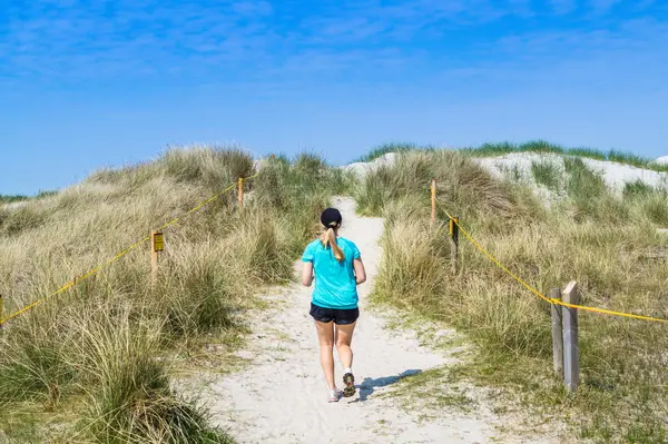 Жінка біжить у дюнах — стокове фото