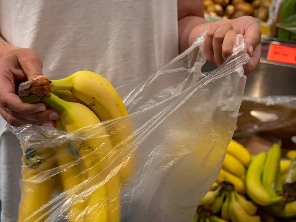Клієнт упаковує банани в пластиковий пакет в супермаркеті — стокове фото