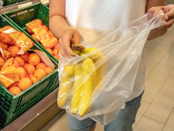 Клієнт упаковує банани в поліетиленовий пакет — стокове фото