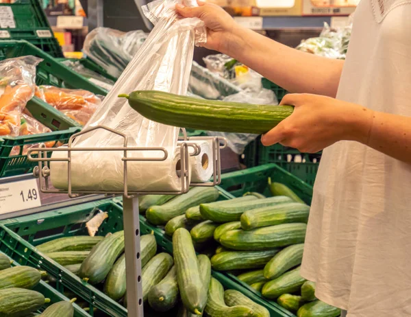 Customer puts cucumber in plastic bag — Stock Photo, Image