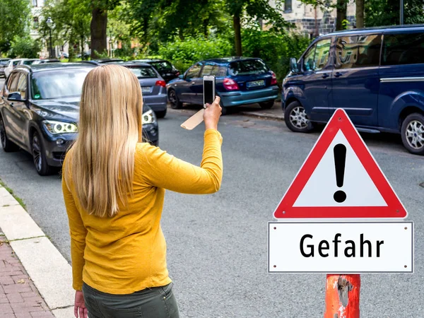 Woman crossing street with cellphone danger german — Stok fotoğraf