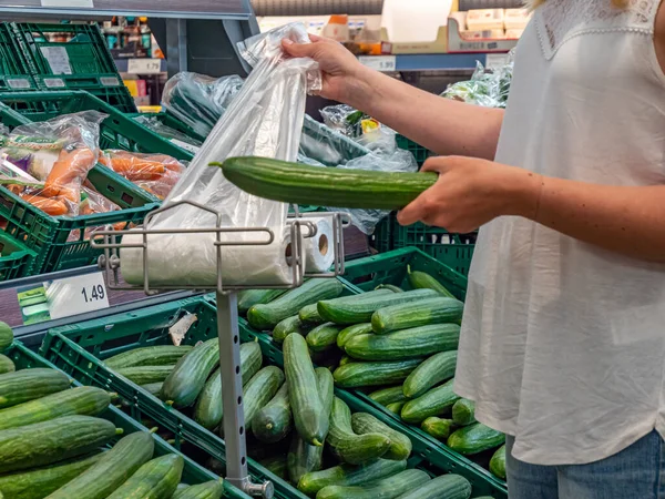 Customer is packing cucumber in plastic bag — Stock Photo, Image