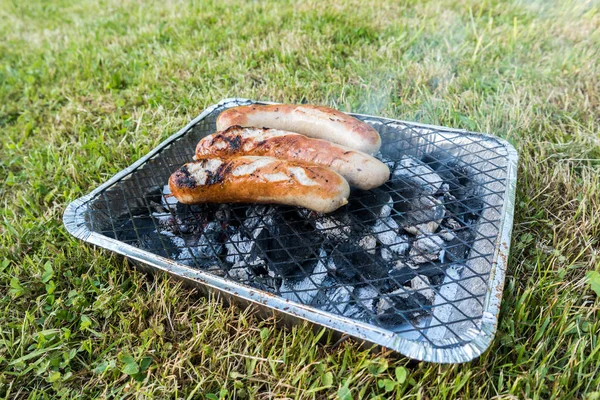 Disposable barbecue with bratwurst — Stok fotoğraf