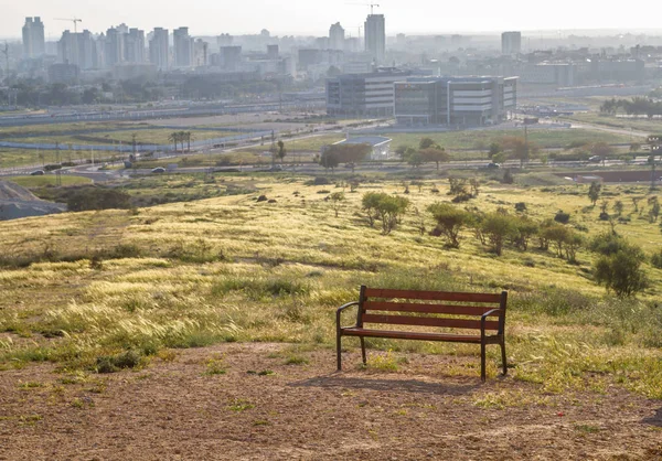 Necef Çölü'nde şehir manzaralı bir tepenin bankta