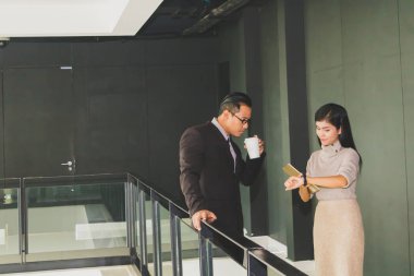 Yöneticiler ve sekreterler kapalı koridorlarda yürüyorlar.