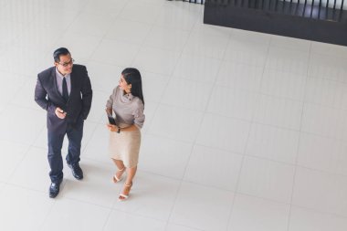 Yöneticiler ve sekreterler kapalı koridorlarda yürüyorlar.