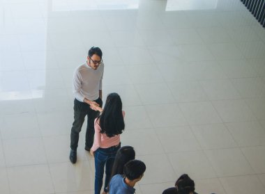 Asyalı ofis çalışanları ofiste el sıkışarak birbirlerini selamlıyorlar.