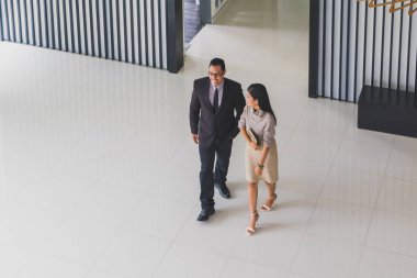 Yöneticiler ve sekreterler kapalı koridorlarda yürüyorlar.