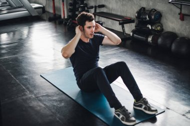 Young man caucasian Being exercised by a sit-up on yoga mat. He 