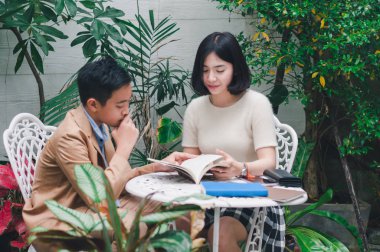 Kız kardeşi evin bahçesinde erkek kardeşine öğretiyor.