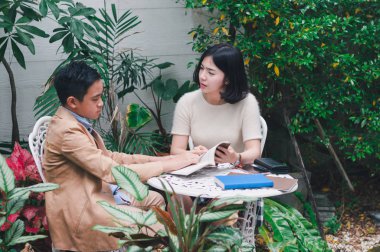 Kız kardeşi evin bahçesinde erkek kardeşine öğretiyor.