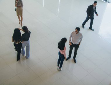 Asyalı ofis çalışanları ofis lobisinde durup konuşuyorlar..