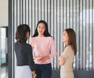 Asyalı ofis çalışanları ofis lobisinde durup konuşuyorlar..