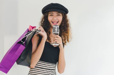 Asyalı kız alışverişi şarkı söylemek için mikrofon kullanıyor. Alışveriş konumu