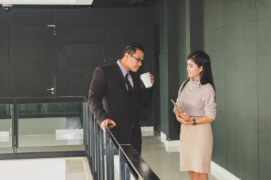 Yöneticiler ve sekreterler kapalı koridorlarda yürüyorlar.