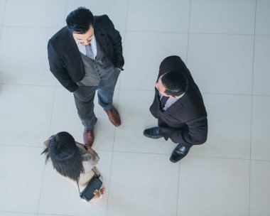 Asyalı ofis çalışanları ofis lobisinde durup konuşuyorlar..