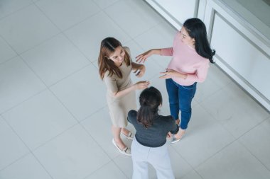 Asyalı ofis çalışanları ofis lobisinde durup konuşuyorlar..