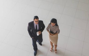 Yöneticiler ve sekreterler kapalı koridorlarda yürüyorlar.