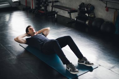 Young man caucasian Being exercised by a sit-up on yoga mat. He 