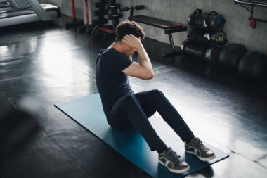 Young man caucasian Being exercised by a sit-up on yoga mat. He 