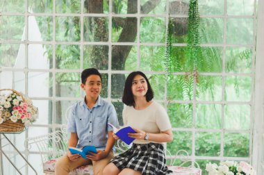 Kız ve erkek kardeş bir saksıda kitap okuyorlar.