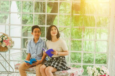 Kız ve erkek kardeş bir saksıda kitap okuyorlar.