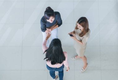 Asyalı ofis çalışanları ofis lobisinde durup konuşuyorlar..