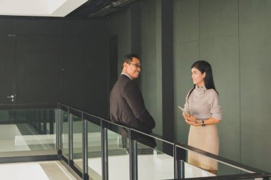 Yöneticiler ve sekreterler kapalı koridorlarda yürüyorlar.