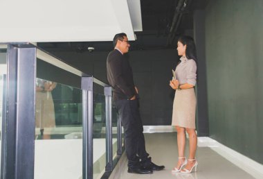 Yöneticiler ve sekreterler kapalı koridorlarda yürüyorlar.