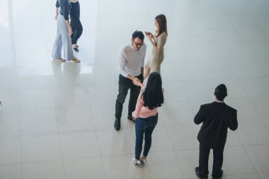 Asyalı ofis çalışanları ofiste el sıkışarak birbirlerini selamlıyorlar.