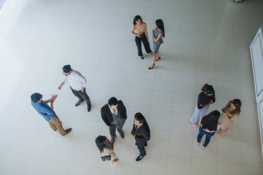 Asyalı ofis çalışanları ofis lobisinde durup konuşuyorlar..