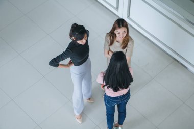 Asyalı ofis çalışanları ofis lobisinde durup konuşuyorlar..