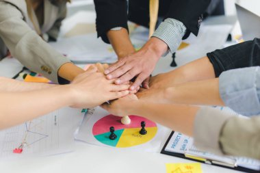 A group of Asian businessmen are discussing. Everyone joins hand