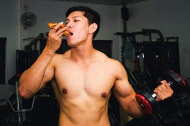 Asyalı adamın kasları var pizza yiyor ve dambılları kaldırıyor.