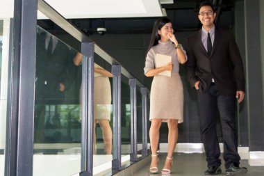 Yöneticiler ve sekreterler kapalı koridorlarda yürüyorlar.