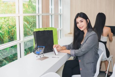 İnternetten alışveriş yapan Asyalı bir kızın portresi. Telefonla ve parayla.