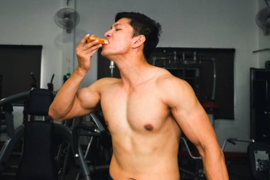 Asyalı adamın kasları var pizza yiyor ve dambılları kaldırıyor.