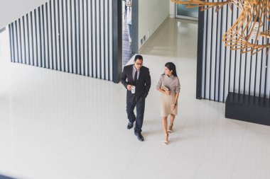 Yöneticiler ve sekreterler kapalı koridorlarda yürüyorlar.