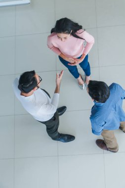 Asyalı ofis çalışanları ofis lobisinde durup konuşuyorlar..