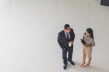 Yöneticiler ve sekreterler kapalı koridorlarda yürüyorlar.