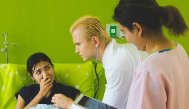 Doktor ve hemşire sethoscop kullanarak kalbi dinliyorlar.