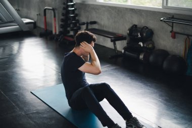 Young man caucasian Being exercised by a sit-up on yoga mat. He 