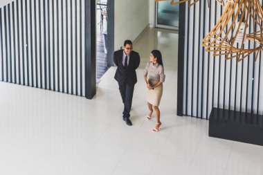 Yöneticiler ve sekreterler kapalı koridorlarda yürüyorlar.