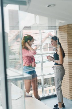 Two beautiful young women drinking coffee and talking together. 