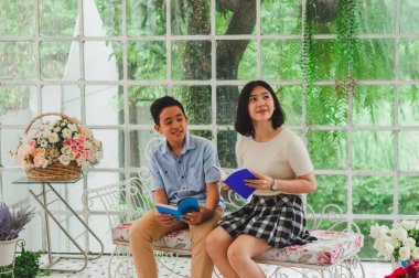 Kız ve erkek kardeş bir saksıda kitap okuyorlar.