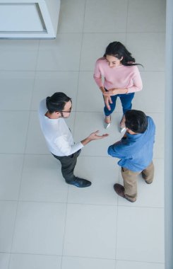 Asyalı ofis çalışanları ofis lobisinde durup konuşuyorlar..