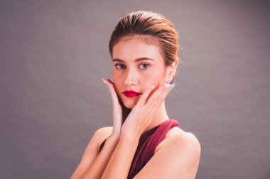 Kırmızı elbiseli güzel bir Asyalı kız GR 'ın önünde duruyor.